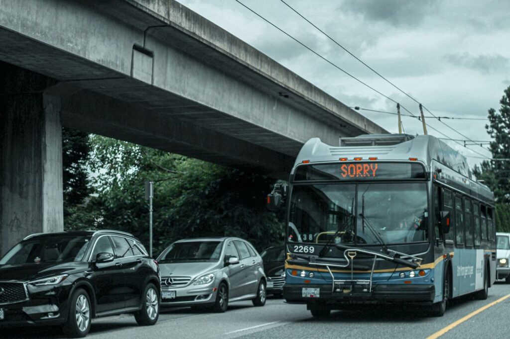 A busy city street with traffic and a bus showing 'SORRY' on its display under an overpass.